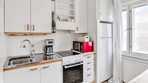 A modern kitchen with white cabinets, a coffee maker, a microwave, and an oven. - Vibrant & Central w Netflix, WiFi, 200m tram/bus (Helsinki)
