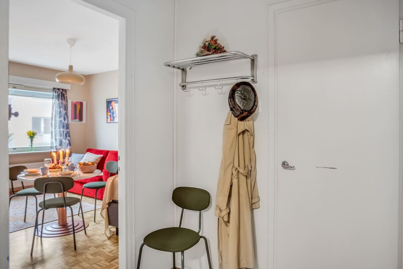 A room with a dining area, a coat rack, and a door.