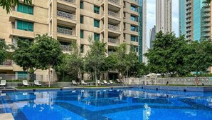 Una piscina al aire libre, sombrillas, sillones reclinables de piscina