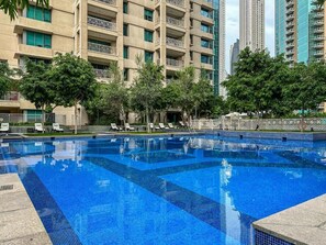 Una piscina al aire libre, sombrillas, sillones reclinables de piscina