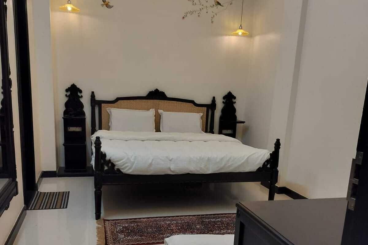 A bedroom with a large bed, a bedside table, a wardrobe, and decorative wall art.