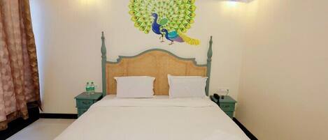 A room with a bed, two bedside tables, a wall mural of a peacock, and two hanging lamps.