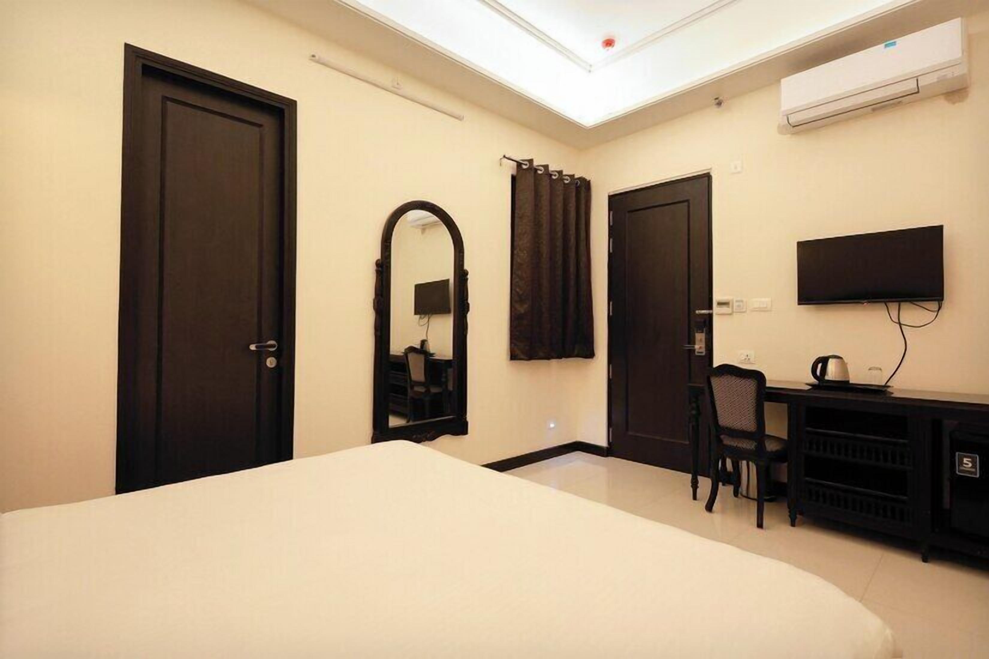 Quarto de hotel com uma cama grande, uma mesa de trabalho com cadeira, televisão e ar condicionado.
