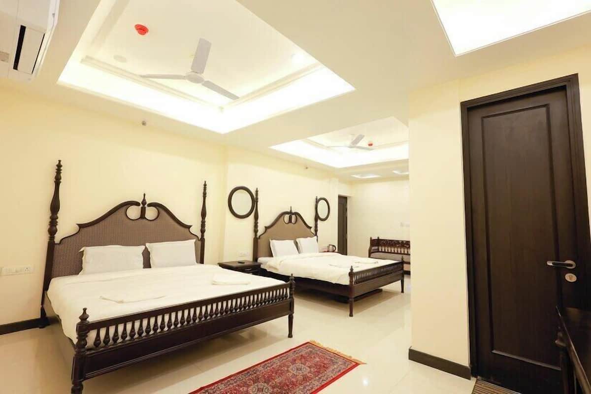 A hotel room with two beds, a skylight, a ceiling fan, and a door.