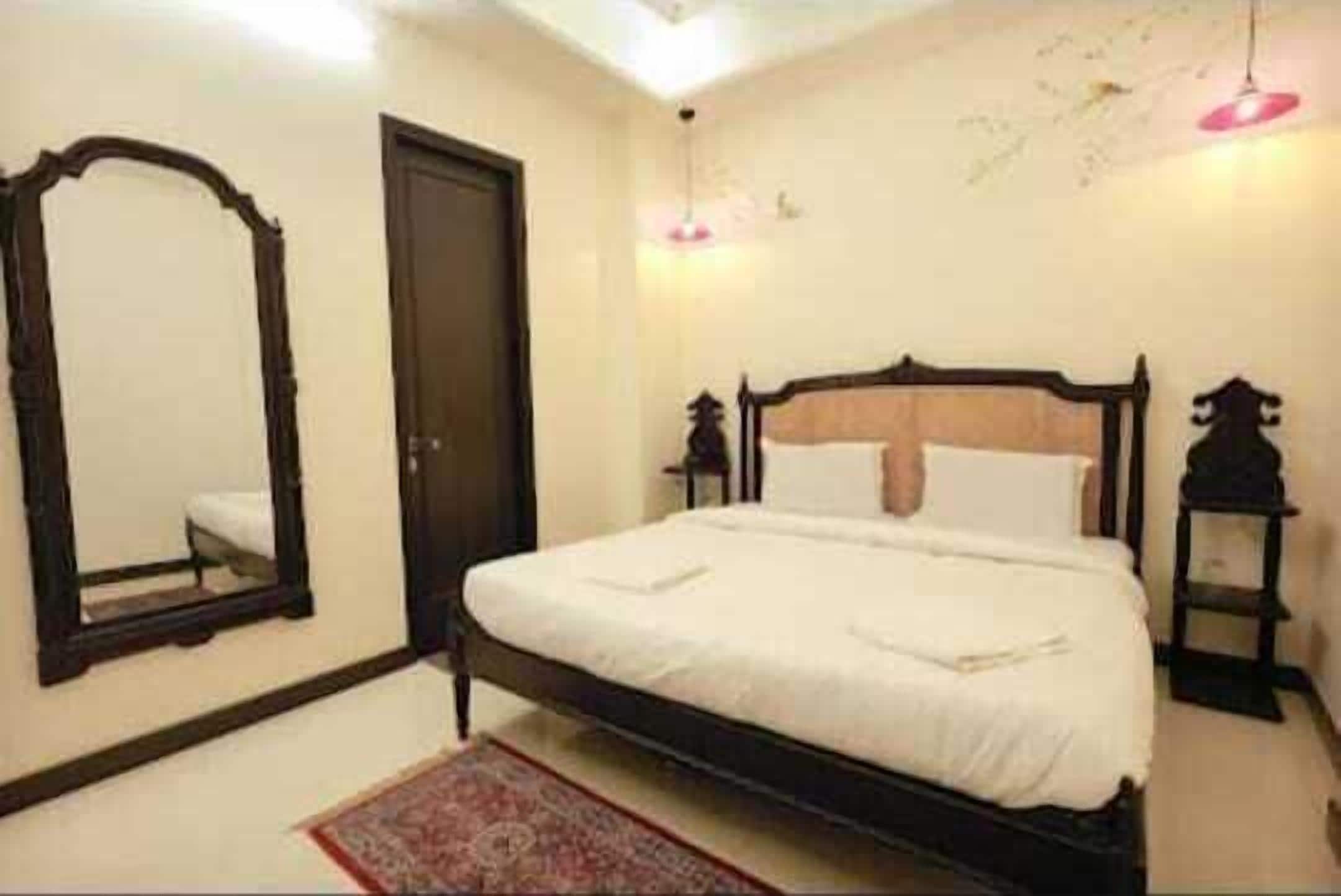 A bedroom with a single bed, a mirror, a door, and a small table.