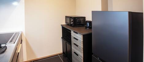 A compact kitchen with a microwave, coffee maker, and a refrigerator.