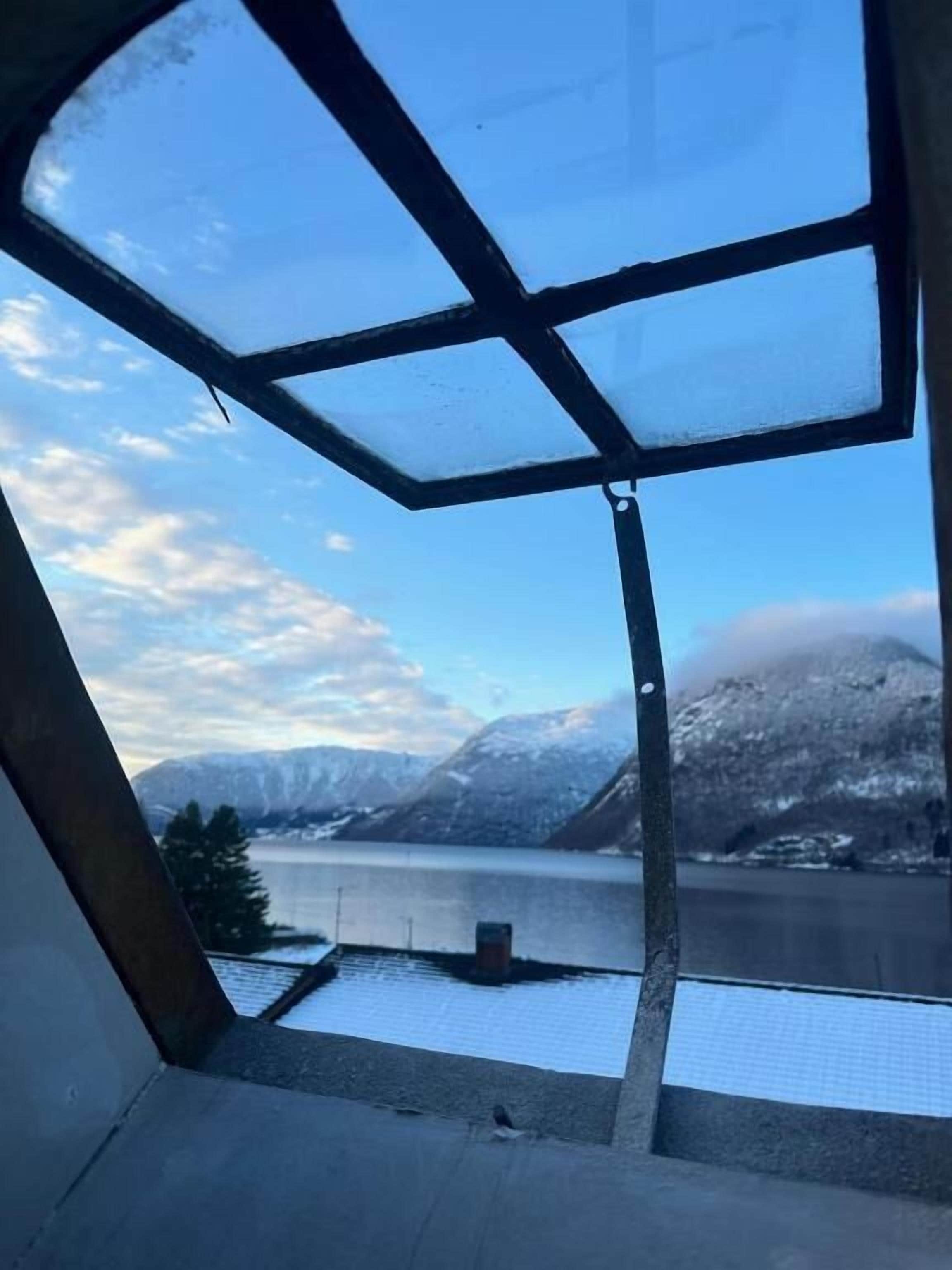 Una habitación con un ventanal grande que da a un lago y montañas.