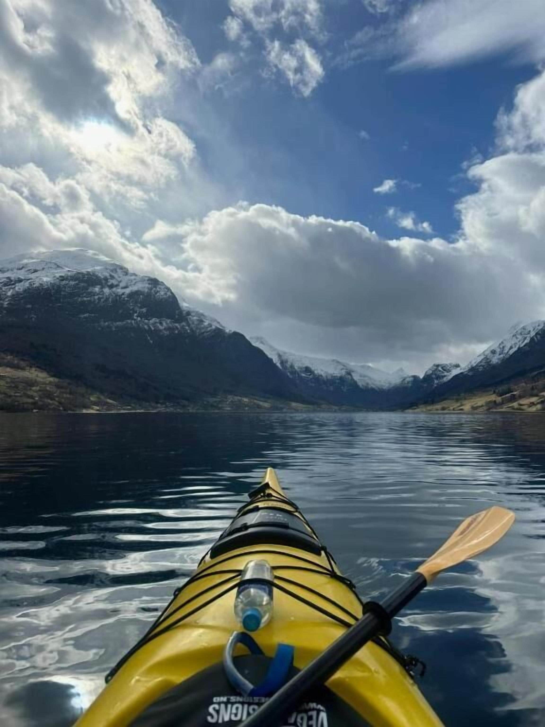 Un kayak sur un lac paisible, avec des montagnes en arrière-plan.