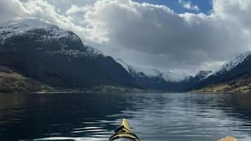 Un kayak sur un lac paisible, avec des montagnes en arrière-plan.
