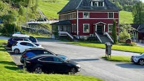 Un edificio rosso con un tetto spiovente, un portico e una strada con auto parcheggiate.