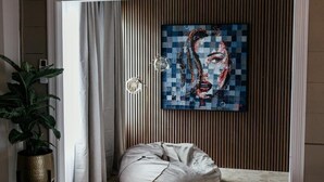 Una stanza con un'ampia finestra, una pianta in vaso, una poltrona sacco e un quadro appeso al muro.