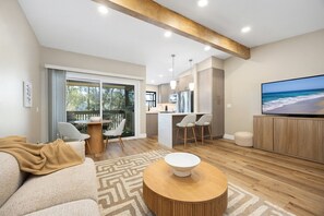 Una sala moderna con un sofá, una mesa de centro y un televisor mostrando una escena de playa.