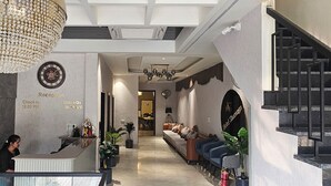 A hotel reception area with a reception desk, a clock, and a chandelier. - Hotel Sharanga (Hisar)