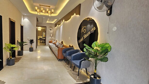 A hotel lobby with a reception desk, seating area, and a lift. - Hotel Sharanga (Hisar)