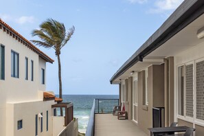 A balcony with a view of the ocean, a palm tree, and a table with chairs. - Thirty-Nine Albatross (Mermaid Beach)
