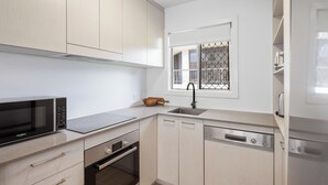 Eine moderne Küche mit Mikrowelle, Backofen, Geschirrspüler und einem Fenster mit Metallgitter.