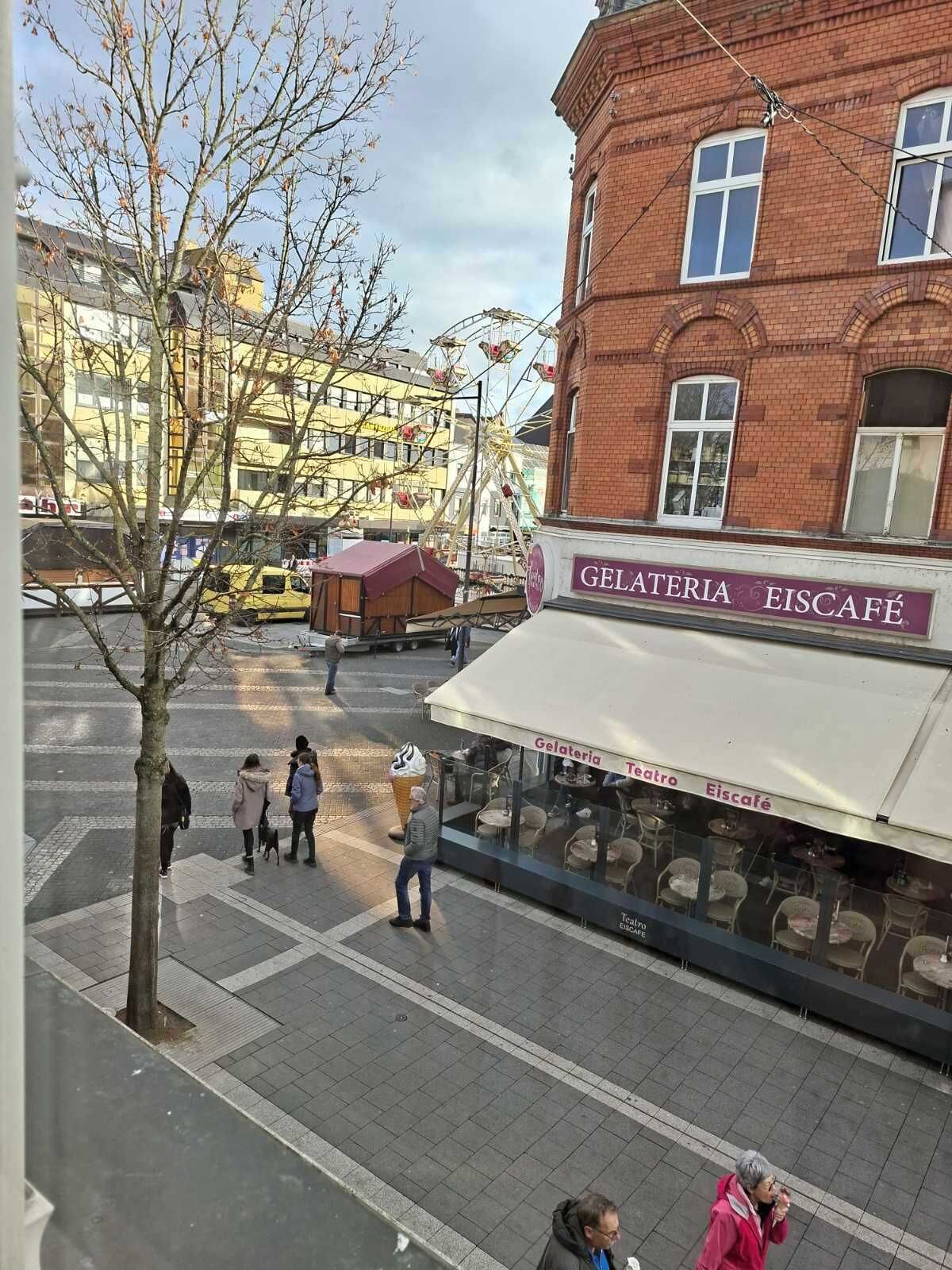 A Gelateria Eiscafé with outdoor seating and a Ferris wheel in the background.