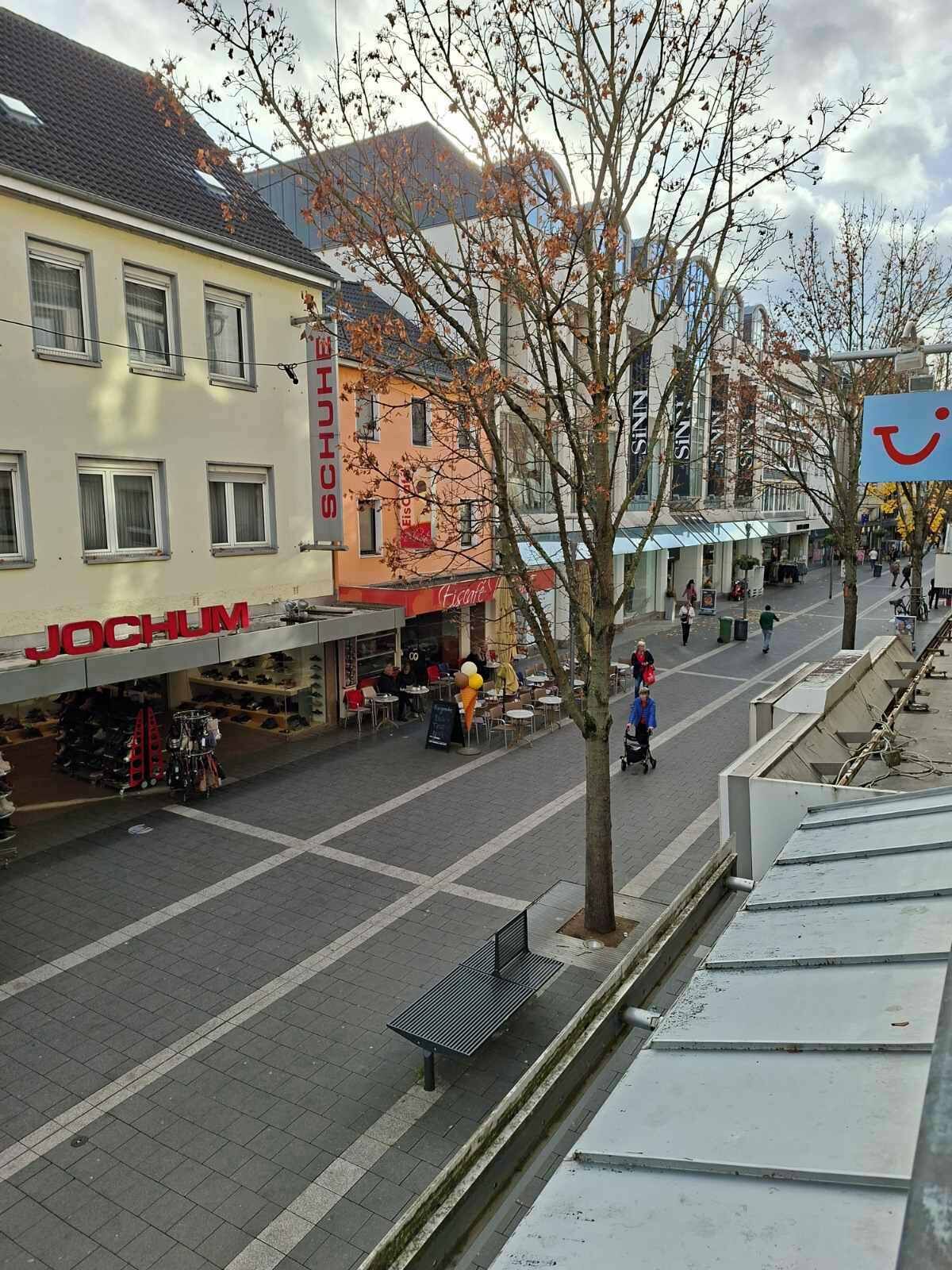 A pedestrian street with shops, including a shoe store named 'JOCHUM'.