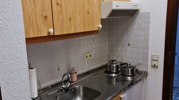 A kitchen with wooden cabinets, a stainless steel sink, and a small refrigerator.