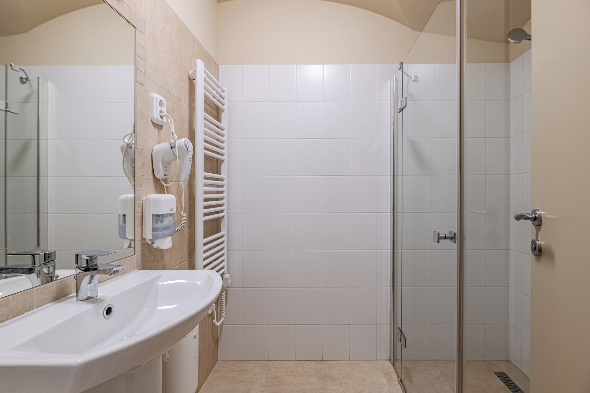 Une salle de bain équipée d’un lavabo, d’un miroir, d’un porte-serviettes et d’une douche à parois de verre.