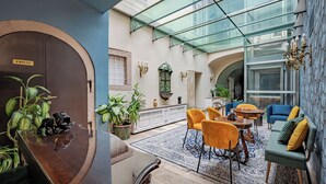 A spacious lobby with a glass ceiling, a reception desk, seating area, and a decorative wall. - Giselle Buda Castle (Budapest)