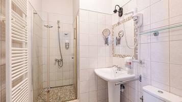 A modern bathroom with a glass-enclosed shower, a white sink, and a toilet.