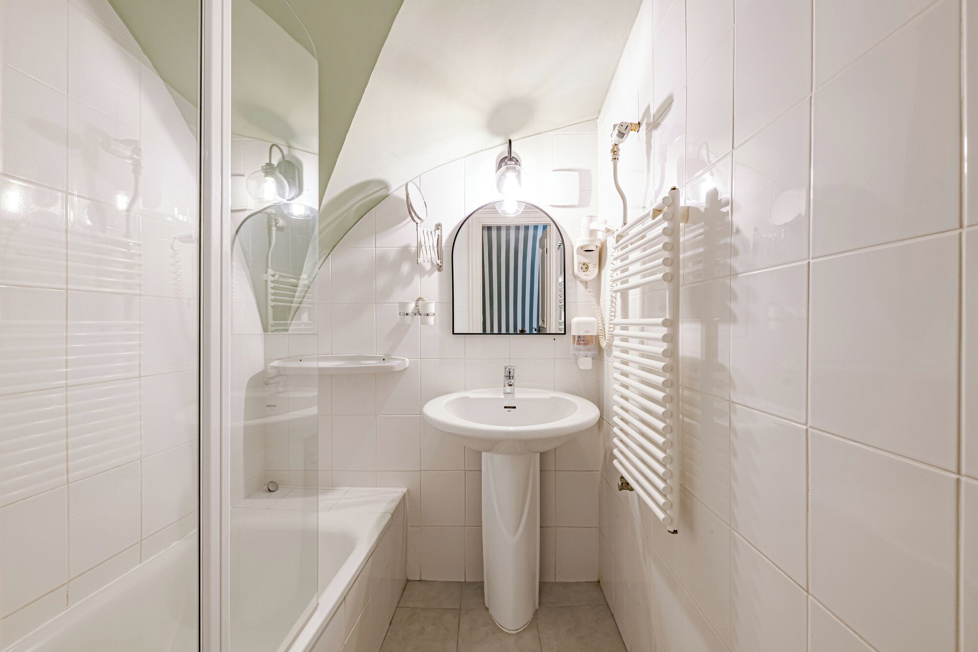 Een moderne badkamer met een wit wastafelmeubel, een glazen douchecabine en een handdoekrek.