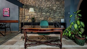 A conference room with a stone wall, a glass table, and a green chair. - Giselle Buda Castle (Budapest)