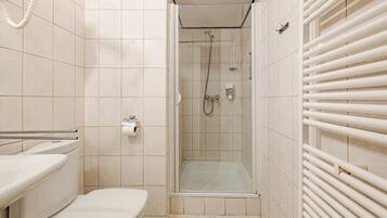 A small bathroom with a toilet, a shower stall, and a towel rack.