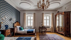 A bedroom with a bed, a desk, a chair, a large mirror, and a chandelier. - Giselle Buda Castle (Budapest)