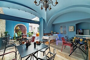A dining area with tables and chairs, a chandelier, and a view of the outside. - Giselle Buda Castle (Budapest)