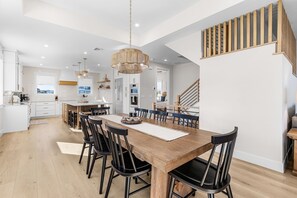 Una cocina moderna con una isla central, mesa de comedor de madera y sillas negras.