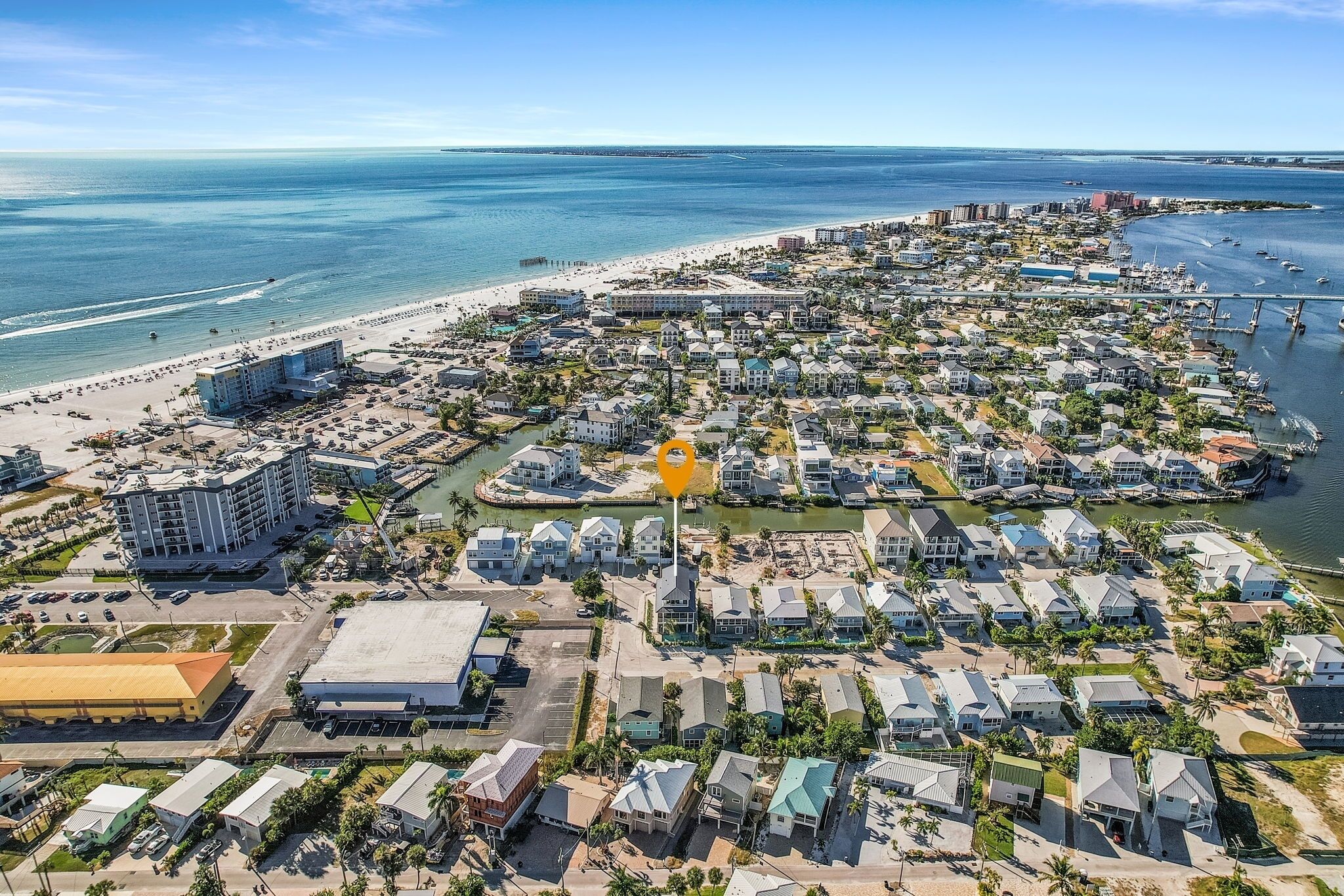 Vista aérea de una zona residencial costera con propiedades frente al mar, un puerto deportivo y un puente que conecta el continente con una isla.