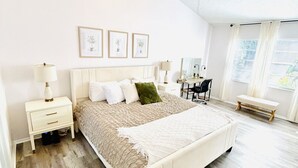 Une chambre à coucher avec un lit, des tables de chevet, un bureau et un ventilateur de plafond.