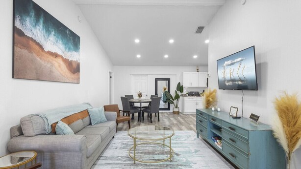 Un salon moderne avec un canapé, une table basse et un téléviseur. Il y a également un coin repas avec des chaises et une table.