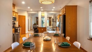 Une cuisine moderne avec des meubles en bois, des appareils en acier inoxydable et un coin repas doté d’une table en bois, mise pour quatre personnes.