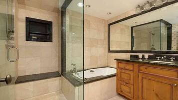 Un baño moderno con ducha envuelta en vidrio, bañera independiente y muebles de madera.