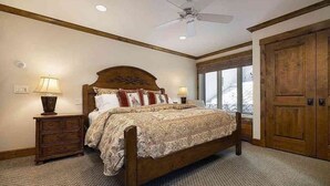 A bedroom with a wooden bed, two bedside tables with lamps, a large window, and a wardrobe. - Treetops 4e 3 Bedroom Condo (Avon)