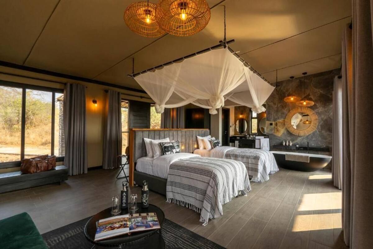 Un dormitorio moderno con una cama grande, mesitas de noche, un tocador y una bañera.
