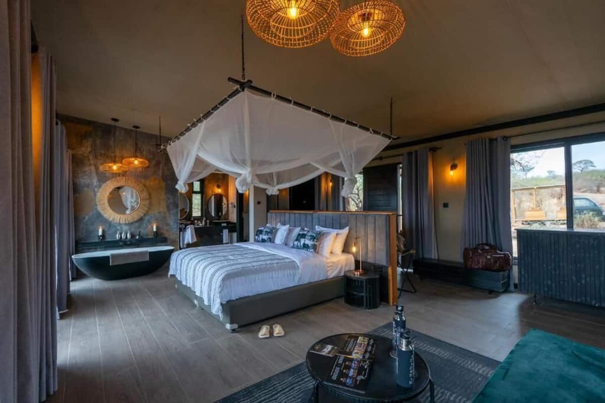 Un dormitorio moderno con cama a dosel, espejo redondo, bañera integrada y vista al exterior.