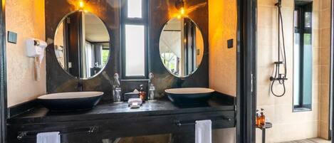 Baño con dos lavamanos, un espejo, secador de pelo y ducha.