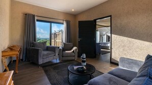 A modern living room with a sofa, armchairs, a coffee table, and a view of the outdoors.