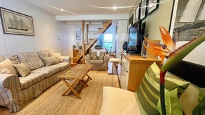 A living room with a sofa, coffee table, and a chair. There is a staircase leading to another room.