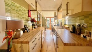 A modern kitchen with wooden countertops, stainless steel appliances, and a view to the outside.
