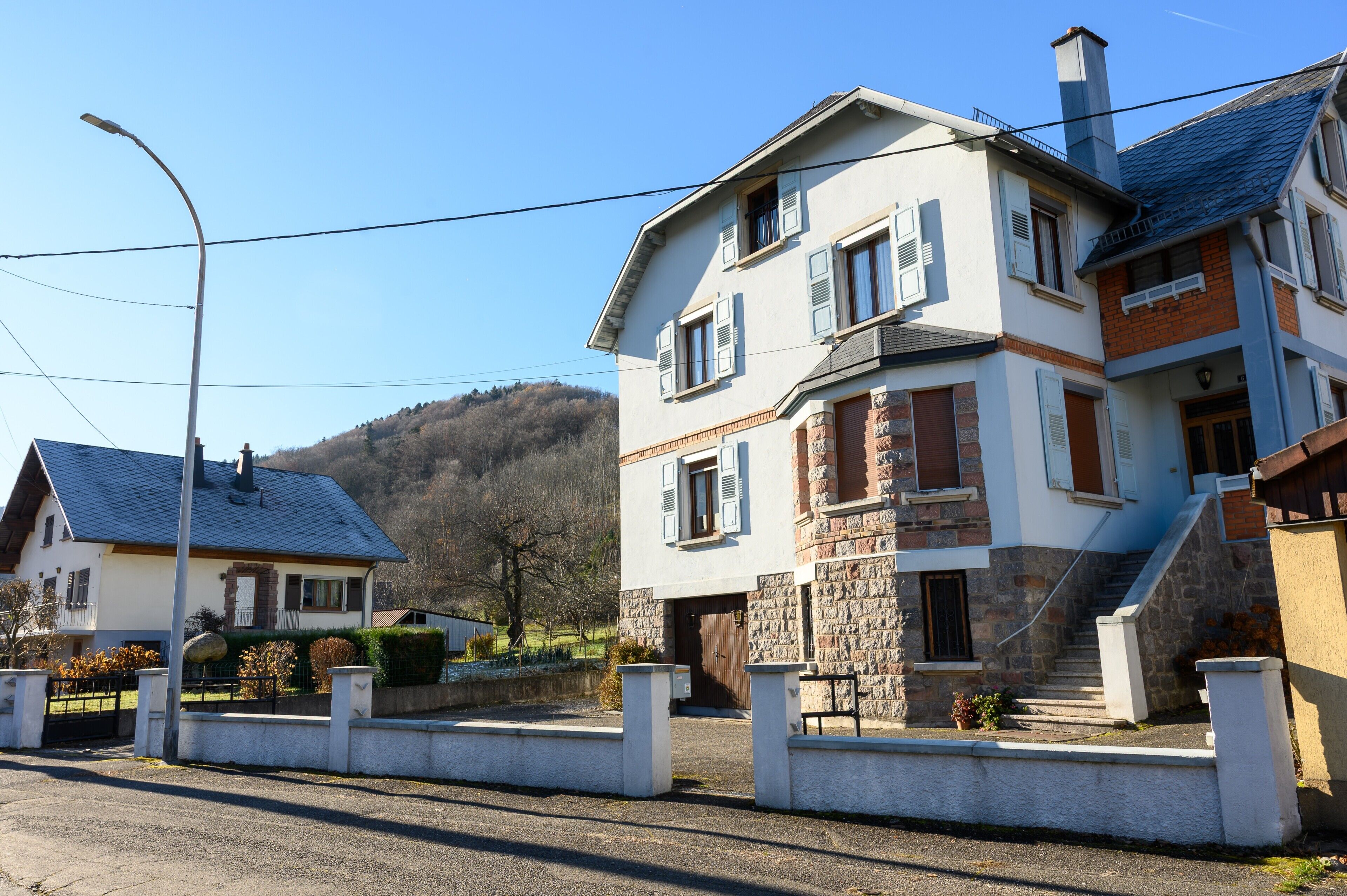 Une maison à deux étages avec une façade en pierre, une porte en bois et un escalier menant à l’étage supérieur.