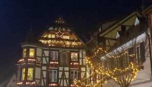 A traditional half-timbered building with a star decoration on the roof, surrounded by string lights. - Apartment 'Le Gîte À Mamie' with Mountain View, Private Terrace and Wi-Fi (Orbey)