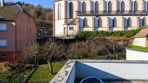 Un bâtiment doté d’un toit en pente, d’une grande fenêtre avec un balcon et surplombant un ciel dégagé.