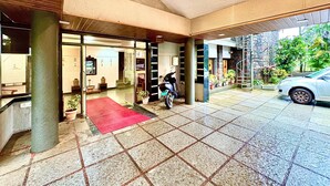 A hotel entrance with a red carpet, tiled flooring, and a parked car. - Honey Bee - A Boutique Resort (Lonavala)