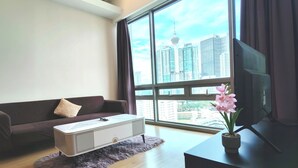 Un salon moderne avec une grande fenêtre, un canapé, une table basse et un téléviseur.