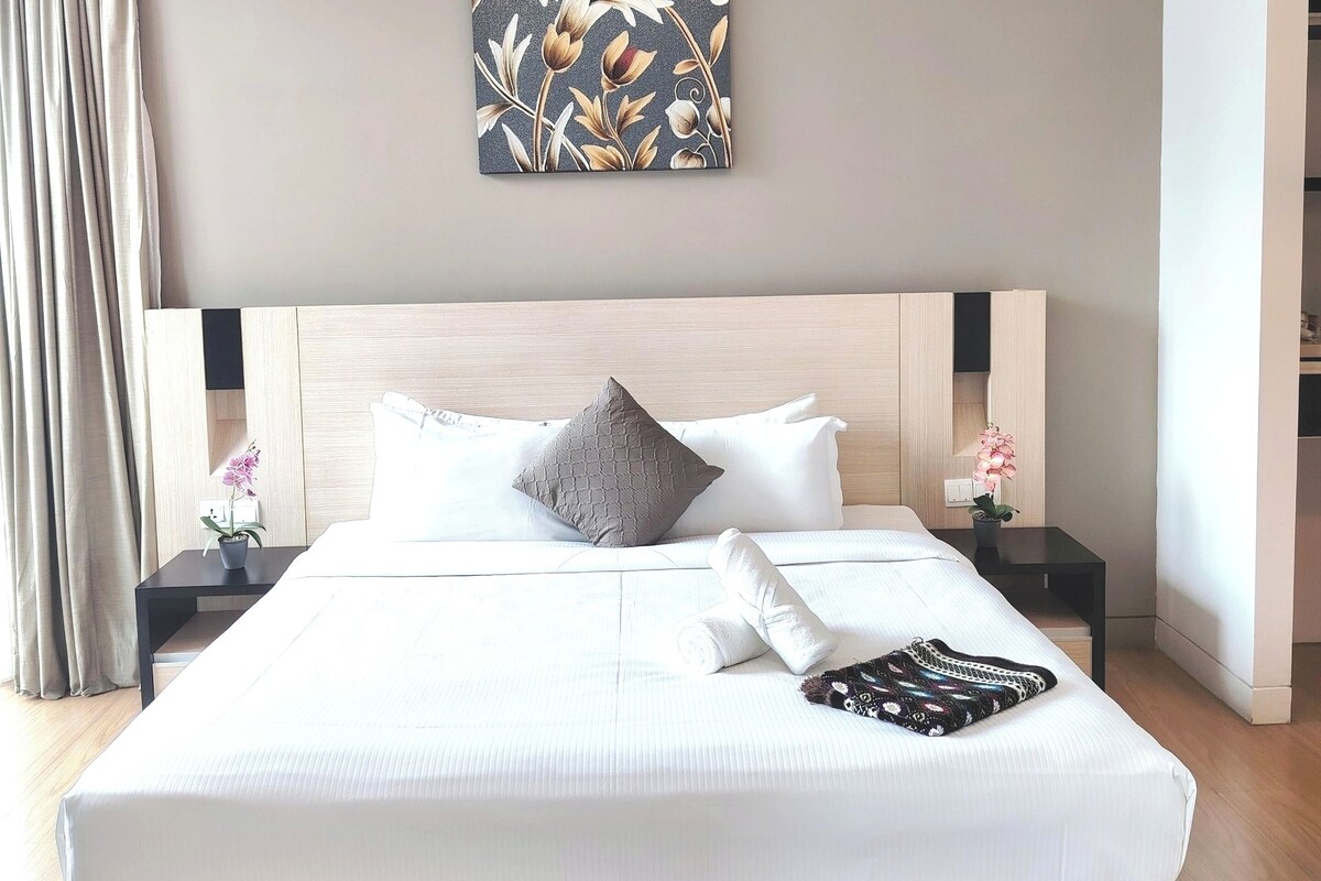 A neatly made bed with a striped mattress, a headboard, and a pillow.